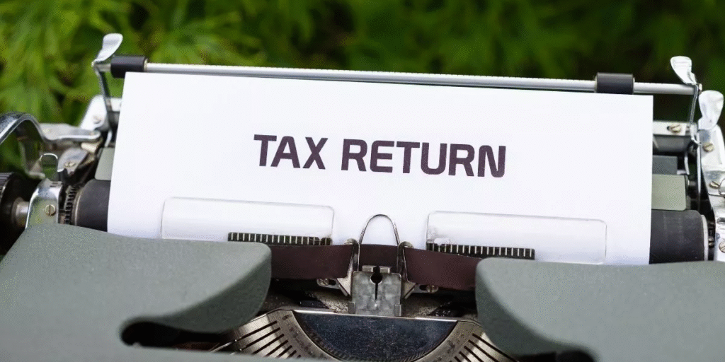 A typewriter with a white paper sheet displaying the bold words "TAX RETURN." The image conveys a sense of formal documentation.