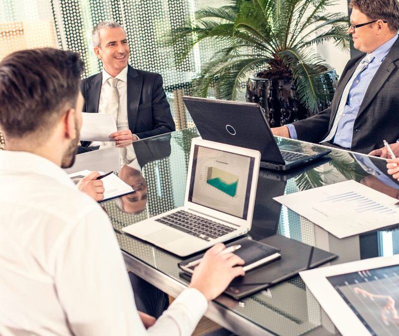 A business meeting around a table with laptops and financial charts